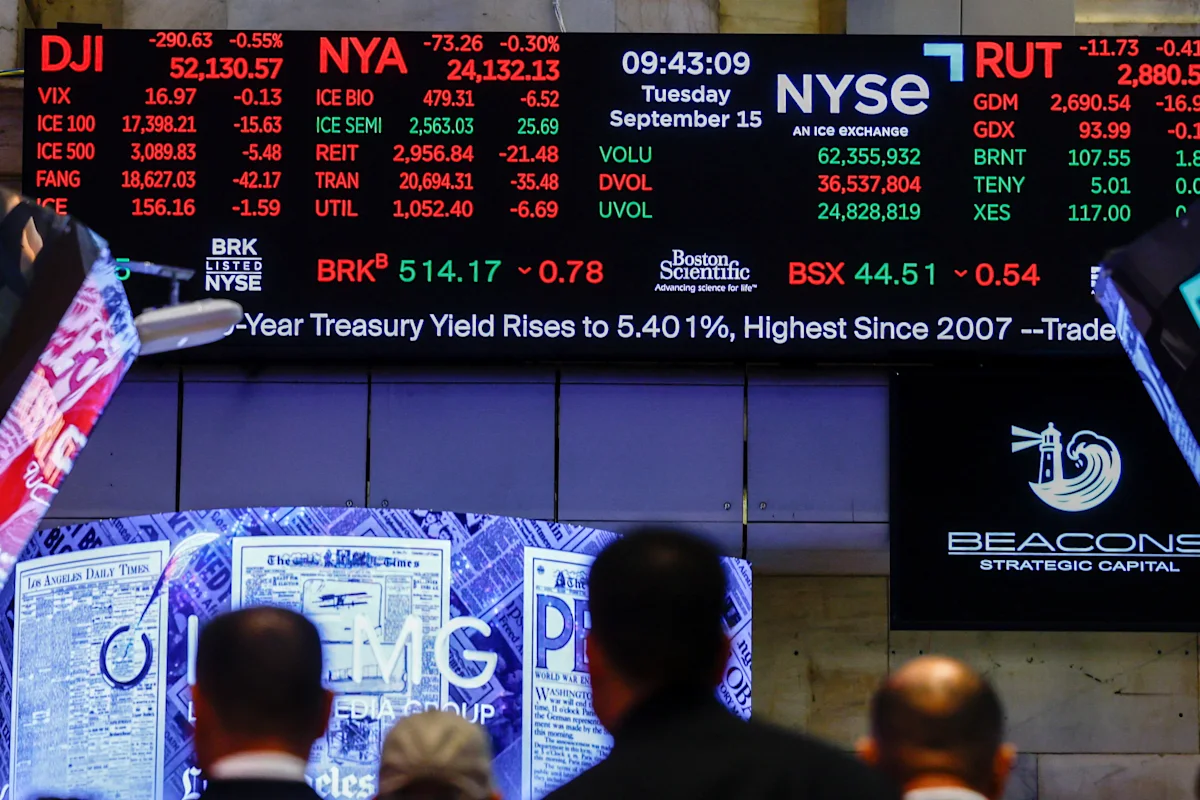 Electronic stock ticker showing market figures above trading floor monitors and silhouetted viewers.