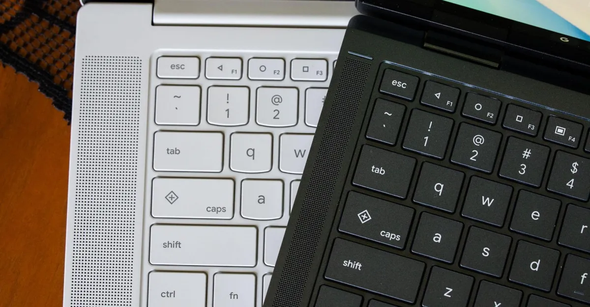 Close-up of white and black laptop keyboards overlapping, showing escape, tab, shift, and letter keys.