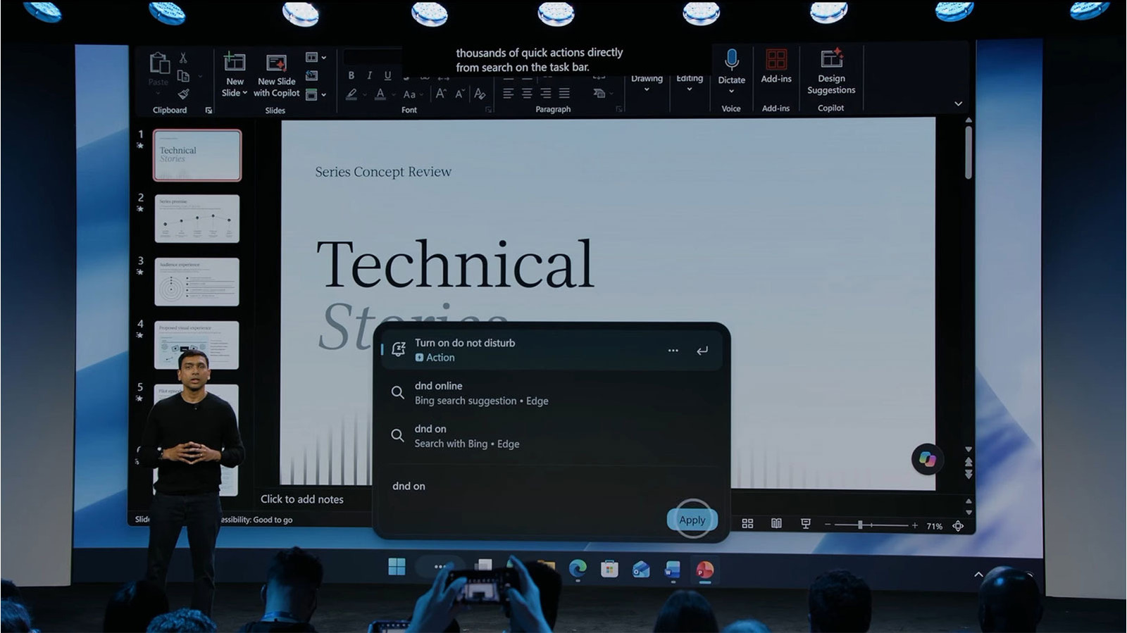 A presenter stands before a projected Windows desktop showing a search panel with a do not disturb action.