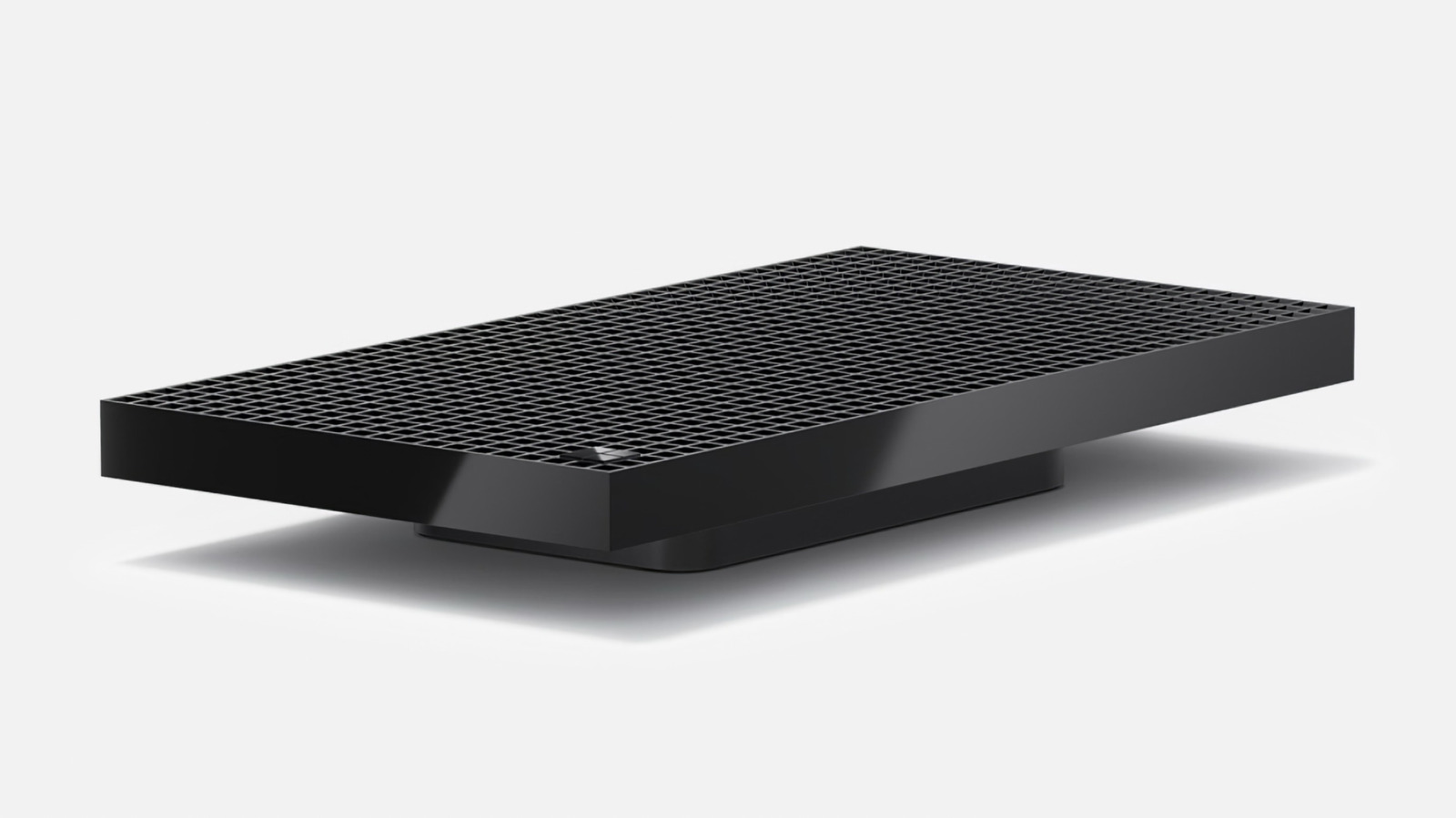 A black rectangular computer device with a grid-patterned top rests against a light background.