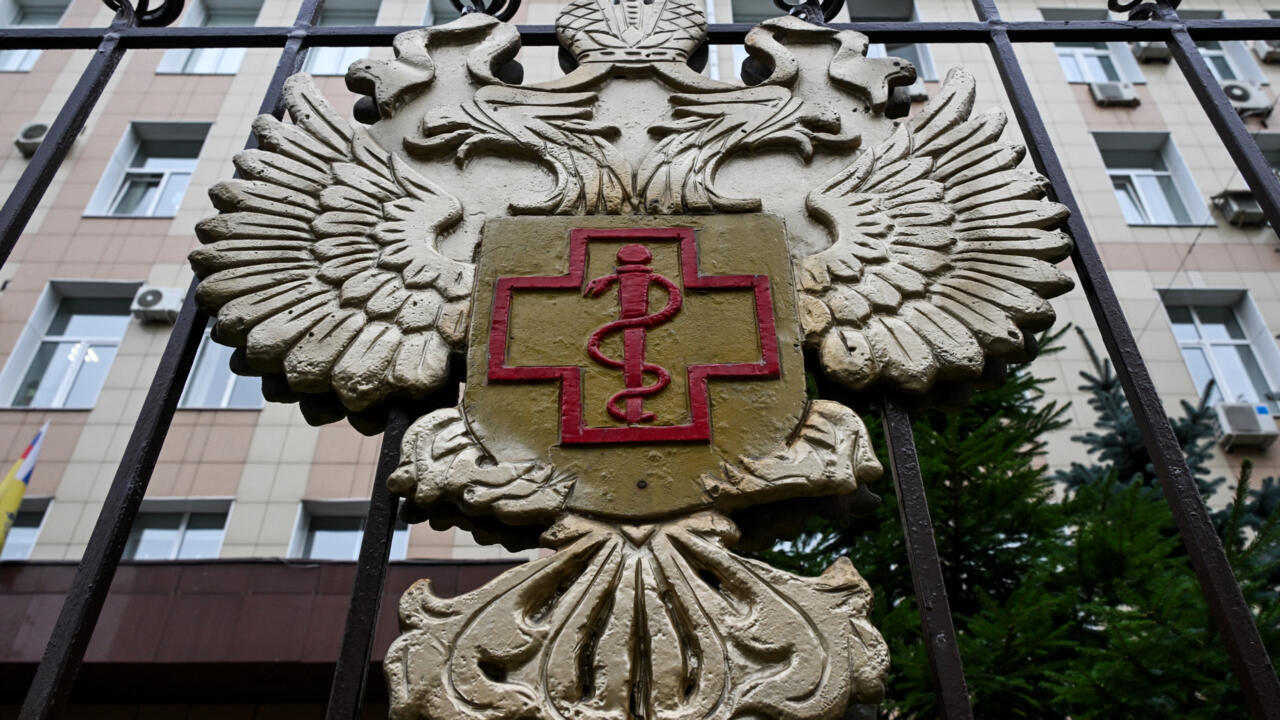 Ornate double-headed eagle emblem with a red medical cross mounted on a black iron fence.