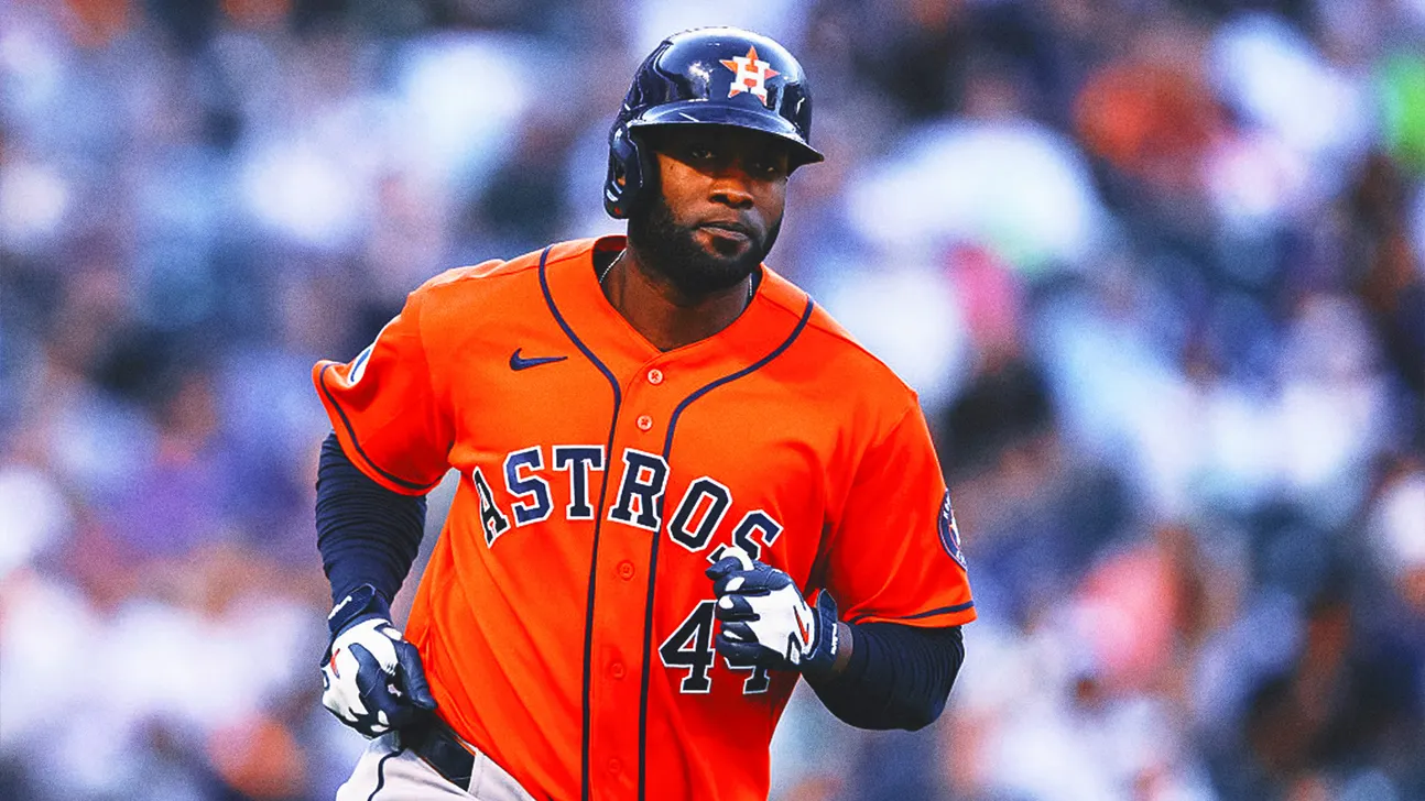 Houston Astros player in an orange uniform and navy helmet runs on the field.