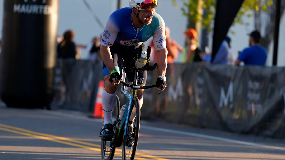 A cyclist in a blue and white racing kit rides a road bike during a race.