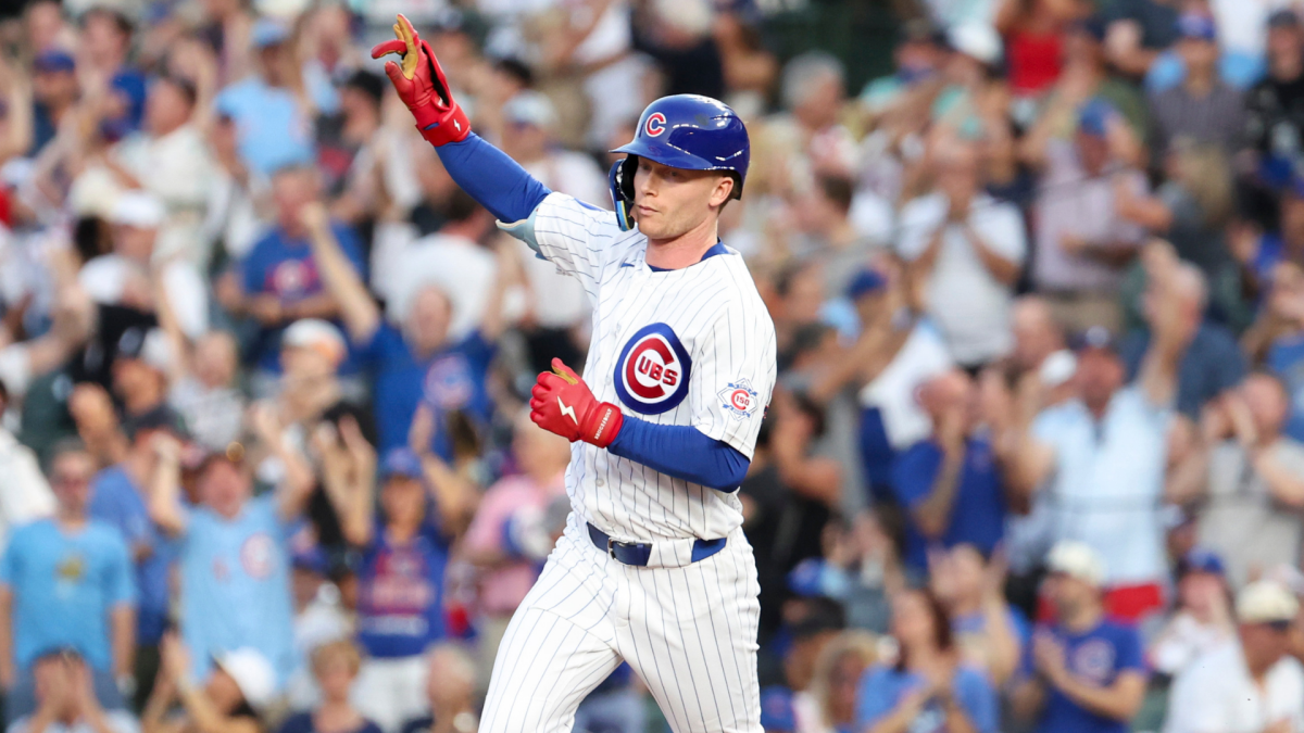 Chicago Cubs player in uniform celebrates with one arm raised before a cheering crowd