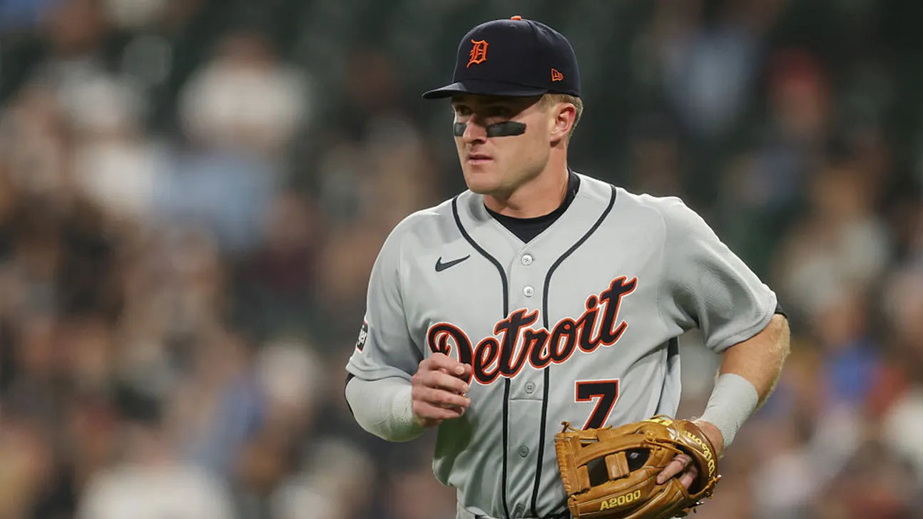 Detroit Tigers player in gray uniform and cap runs while holding a baseball glove.