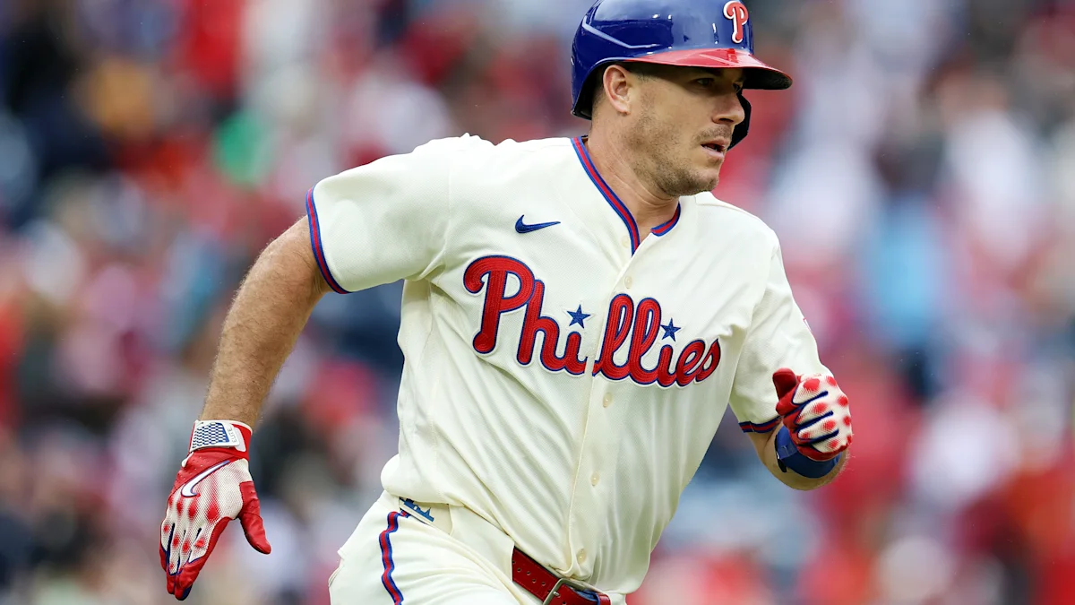 Philadelphia Phillies player in a white uniform and blue helmet running on the field.