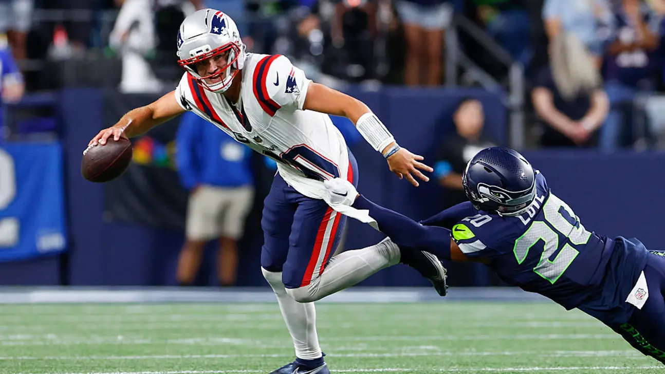 A New England quarterback evades a Seattle defender during an NFL game.