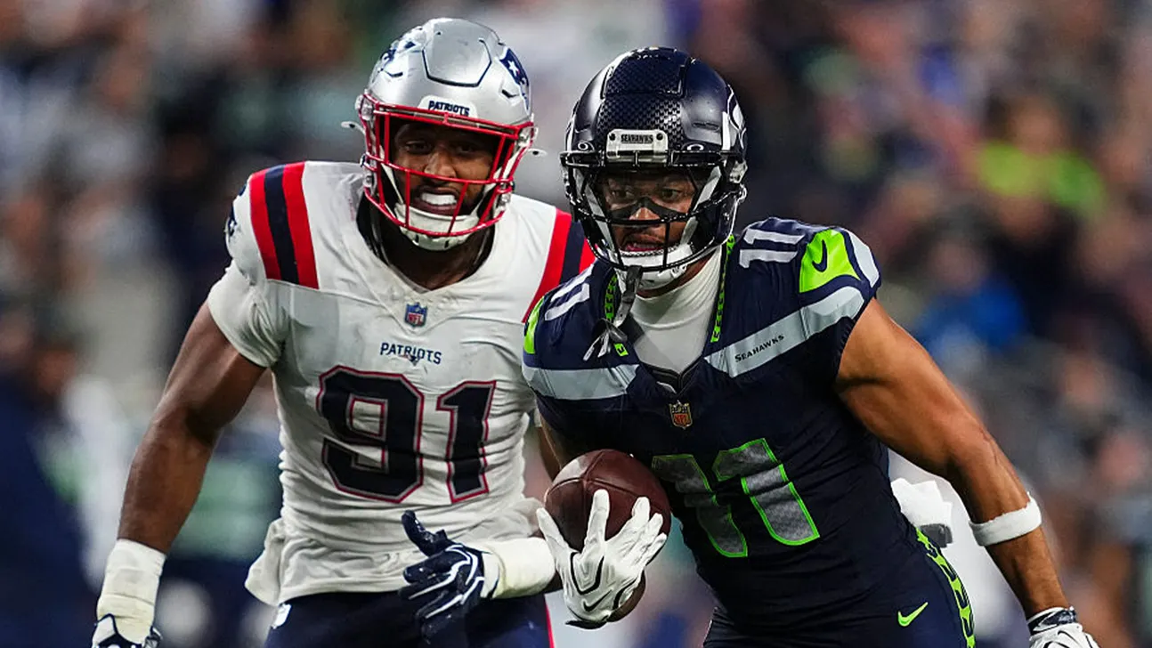 Two NFL players, one in Patriots white and one in Seahawks navy, compete during a game.
