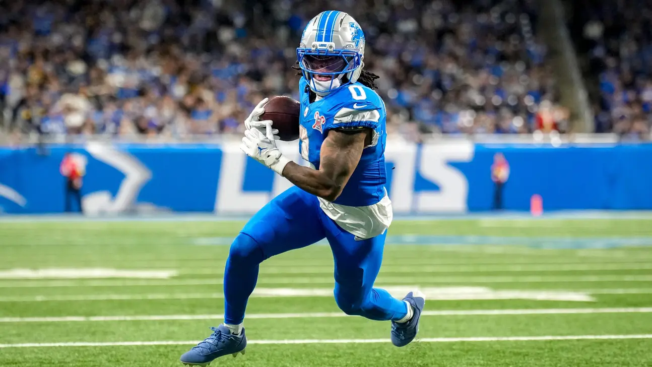 Detroit Lions football player runs with the ball during a game on a green field