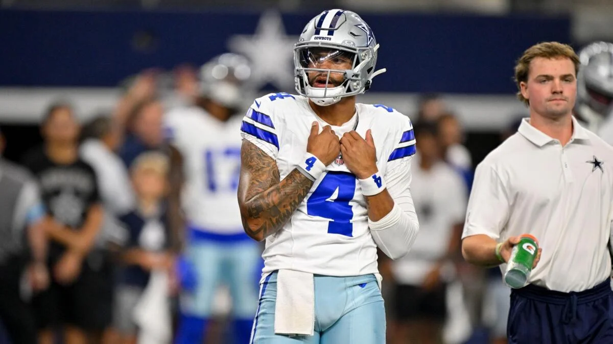 Dallas Cowboys quarterback wearing number 4 stands on the sideline in uniform.