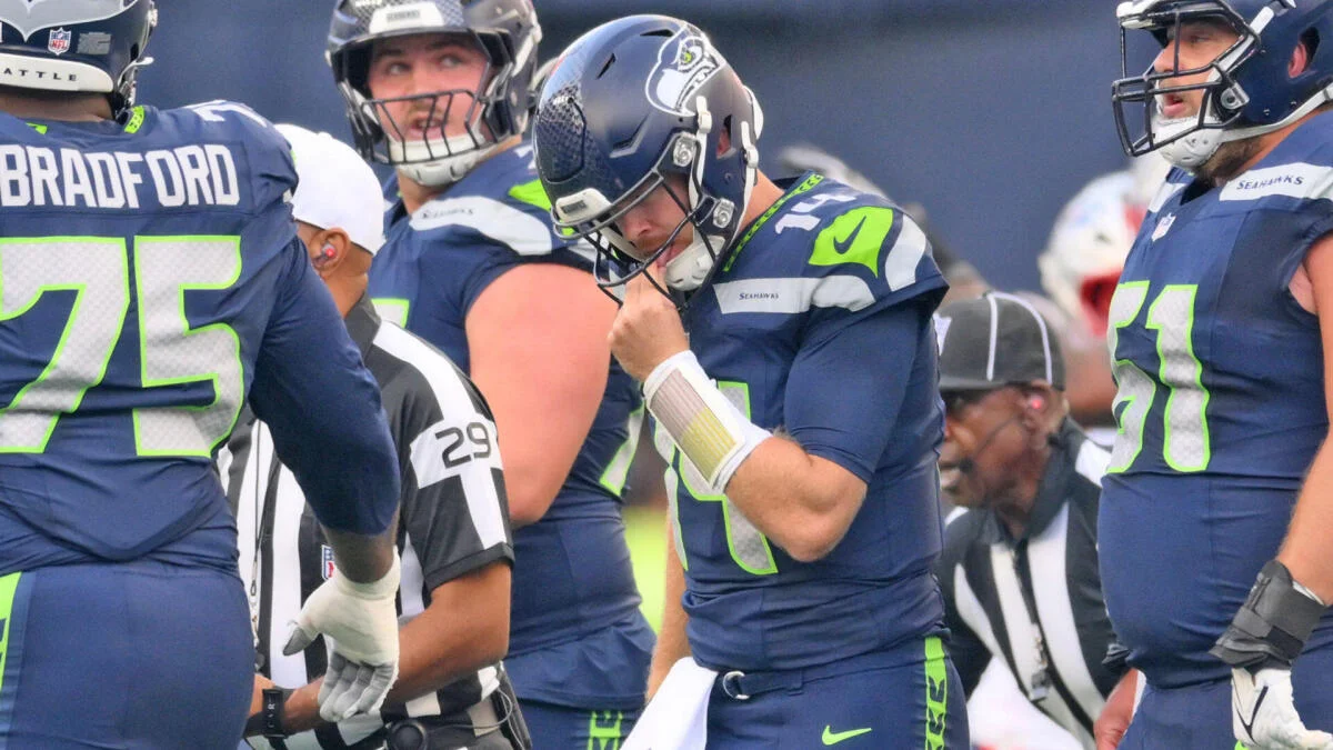Seattle Seahawks players gather around quarterback Sam Darnold during a game