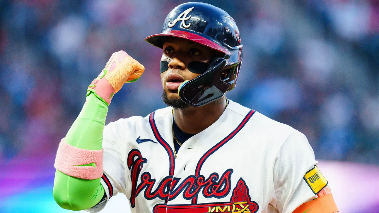 Atlanta Braves player in a white uniform and helmet raises a gloved fist.