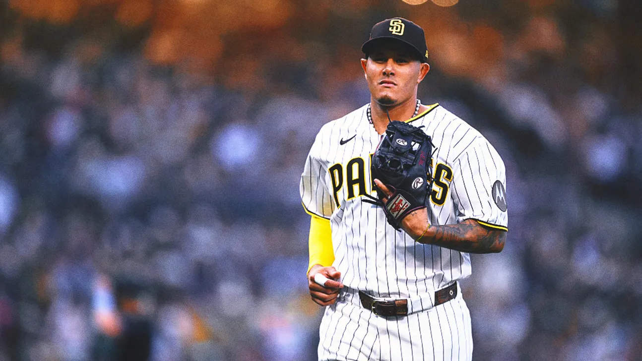 Padres pitcher in a white pinstriped uniform holds his glove against a blurred stadium crowd.