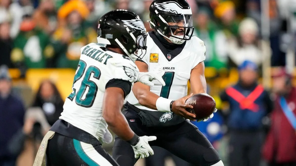 Two Philadelphia Eagles players in white uniforms exchange the football during a game