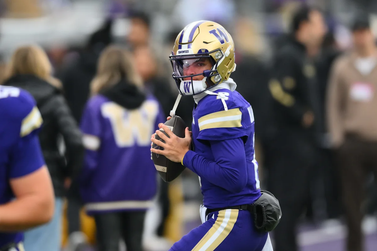 Football player in purple and gold uniform grips the ball during a game