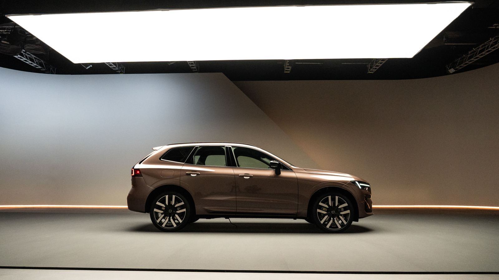 Brown Volvo SUV displayed in profile inside a dimly lit studio beneath a large softbox