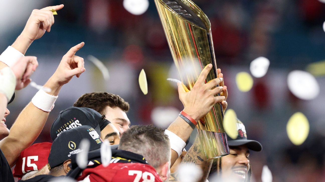 Football players celebrate while raising a championship trophy amid falling confetti.