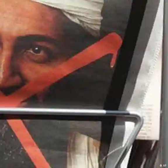 Close-up of a man's face partially obscured by red and black diagonal shapes in a framed image.