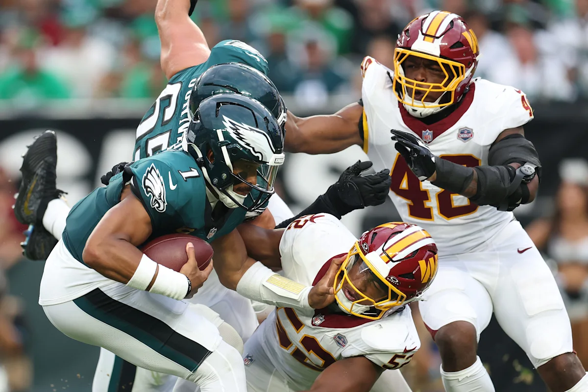 Eagles ball carrier is tackled by two defenders in NFL game action