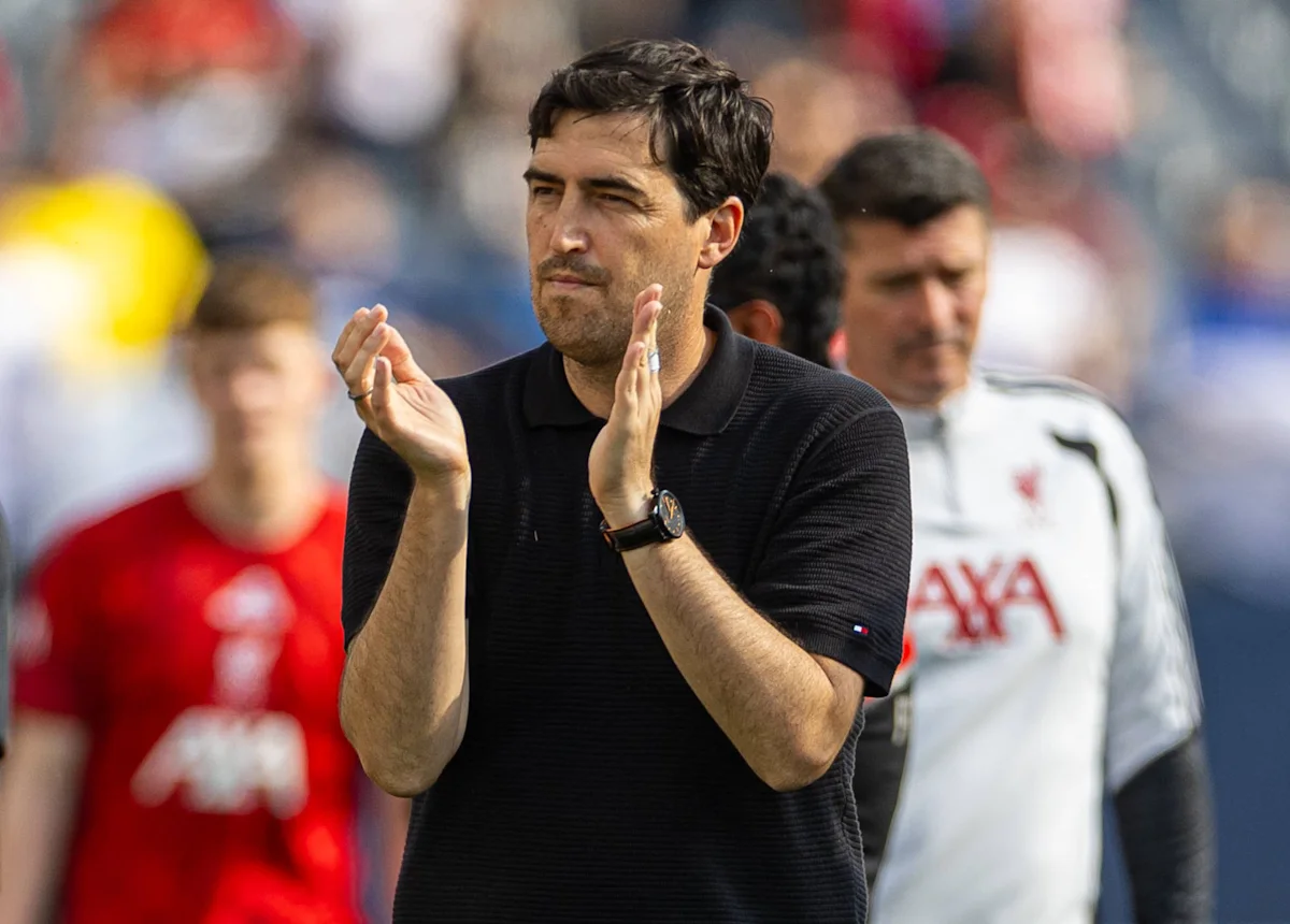 Football manager in black polo applauds from the touchline during a match
