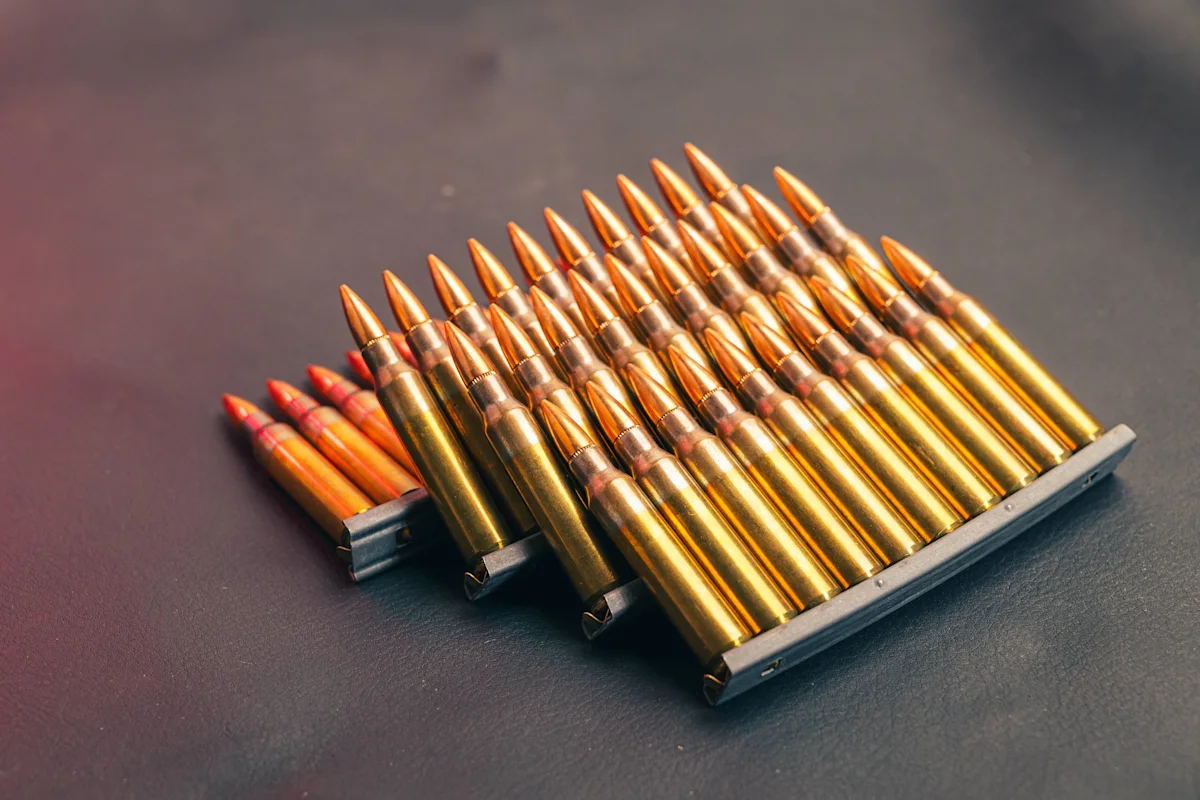 Rows of brass rifle cartridges arranged in metal ammunition clips on a dark surface