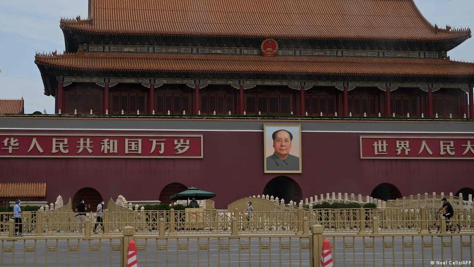 Portrait of Mao Zedong displayed on a traditional Chinese building above a guarded pedestrian area
