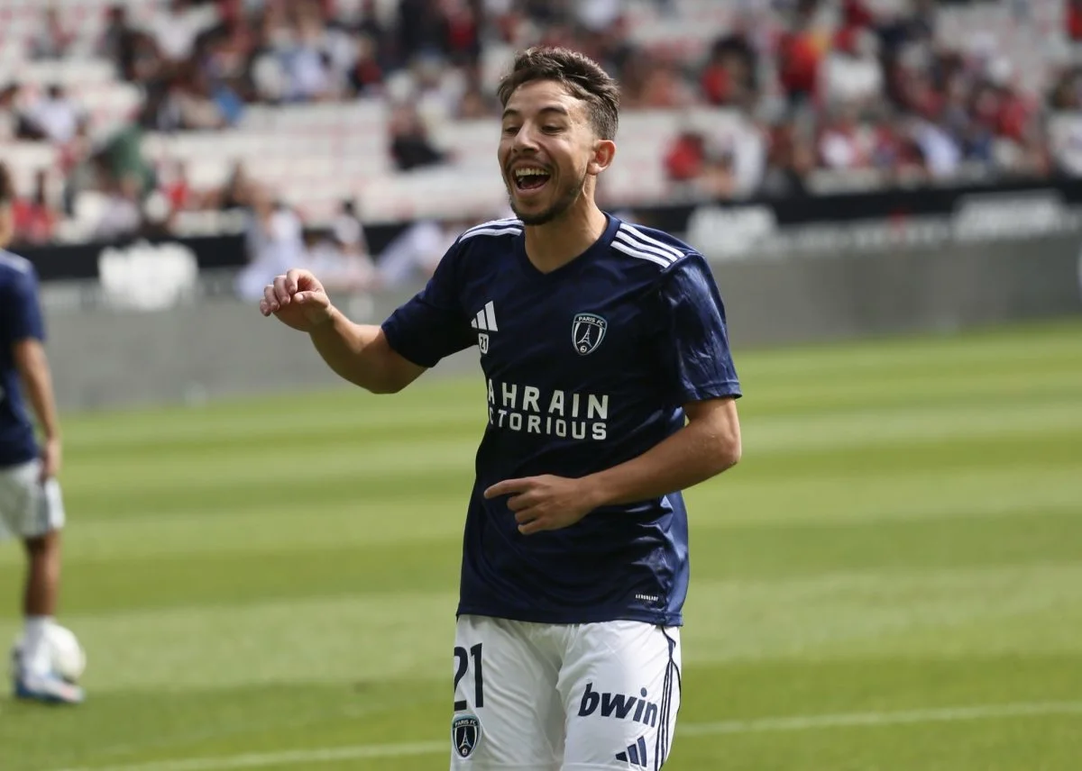 Footballer in navy Paris FC kit smiling and gesturing during a match