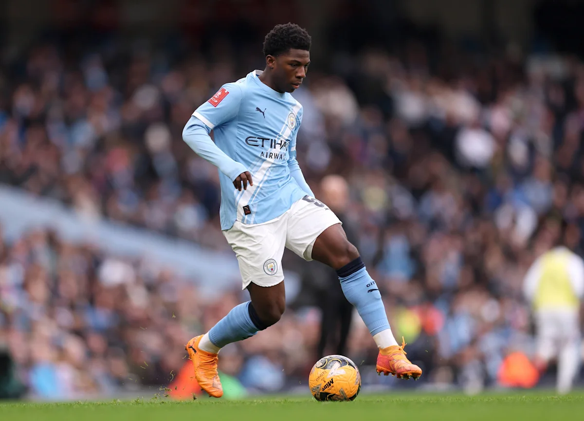 Young Manchester City footballer dribbling a ball across the pitch during a match
