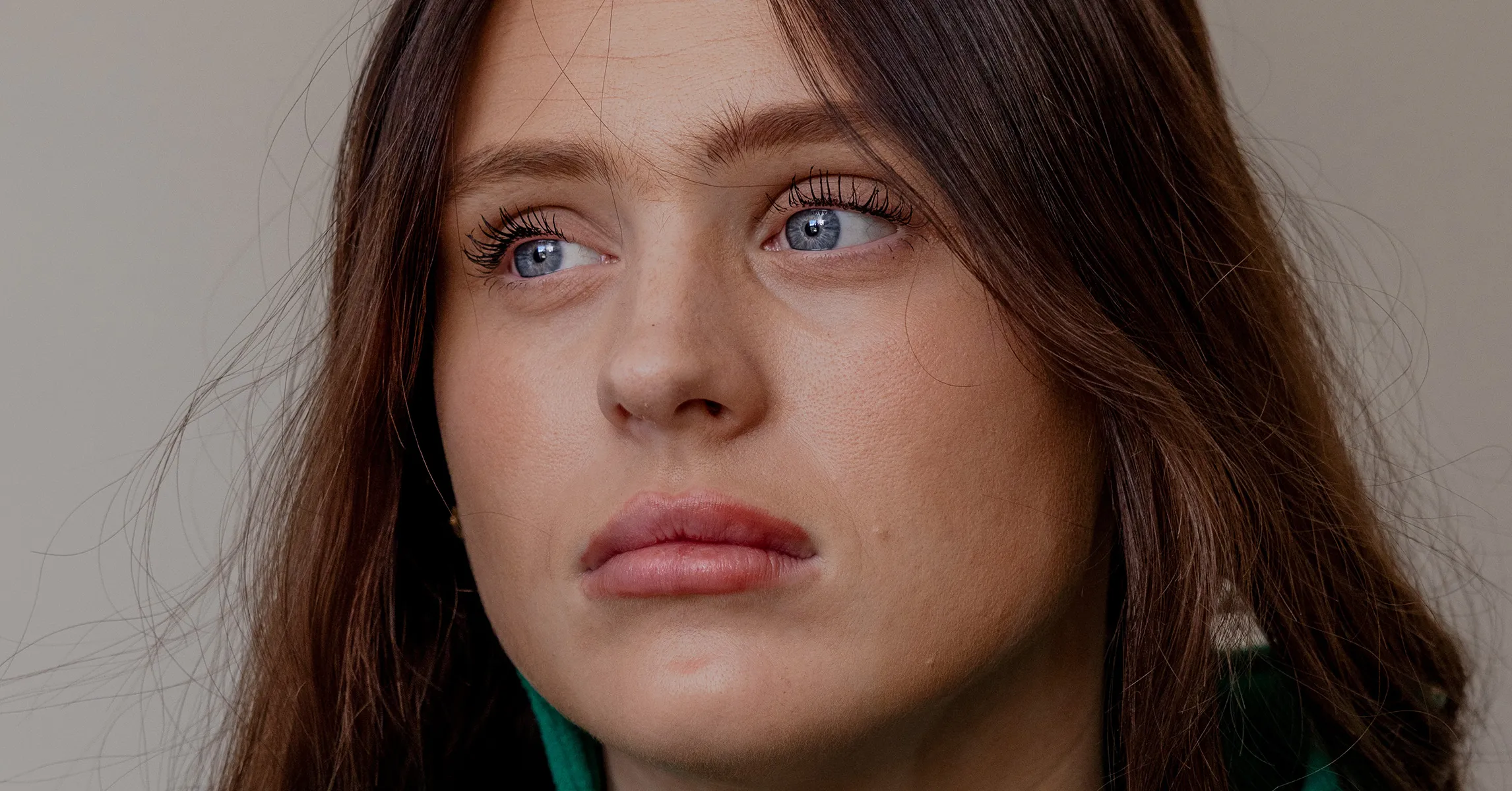 Close-up portrait of a young woman with brown hair, blue eyes, and a neutral expression.