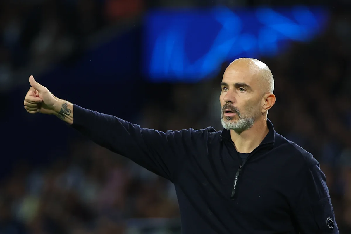 Bald, bearded football coach giving a thumbs-up while gesturing during a match