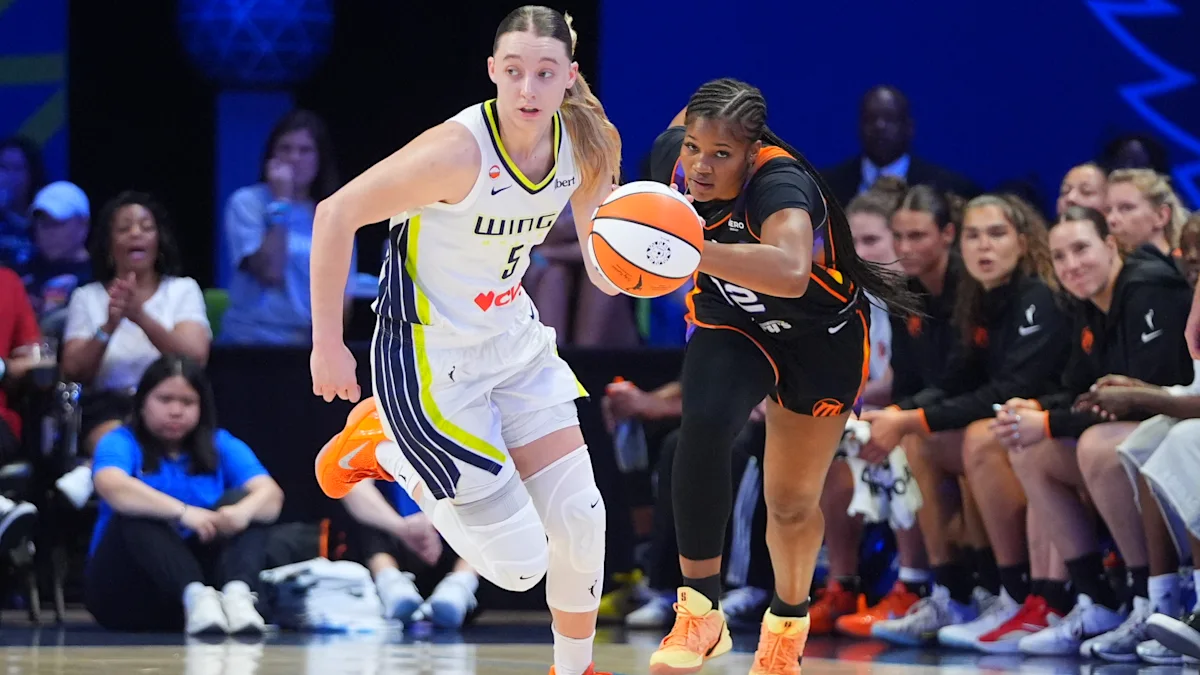 Two basketball players compete for the ball as spectators watch from courtside.
