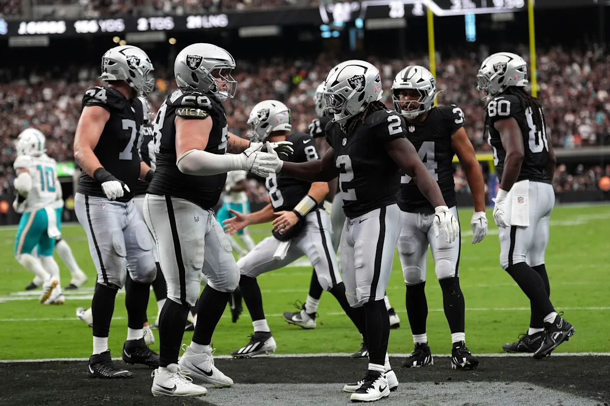 Las Vegas Raiders players in black uniforms gather on the football field during a game