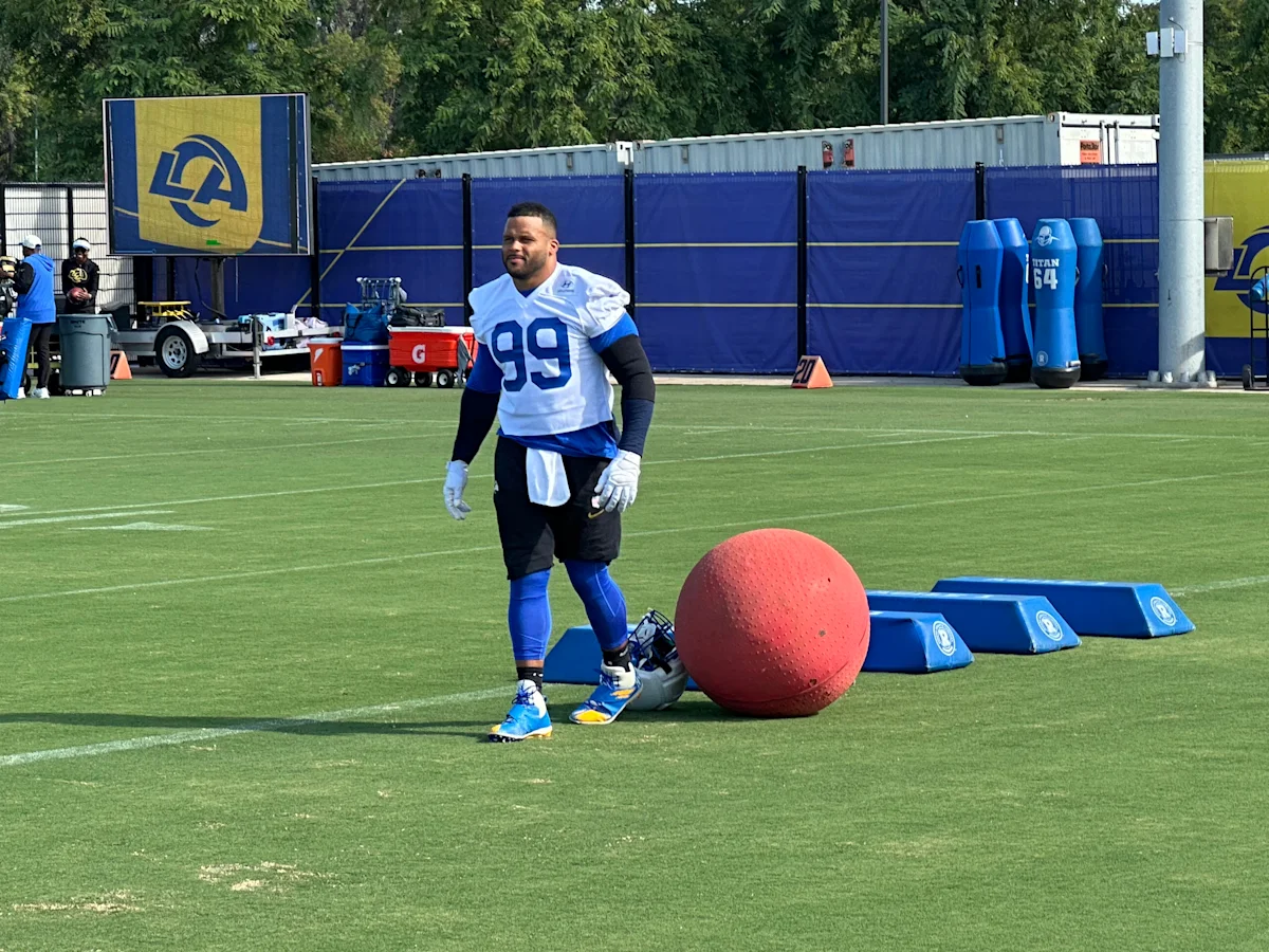 Football player wearing number 99 stands beside a red medicine ball during a practice session.