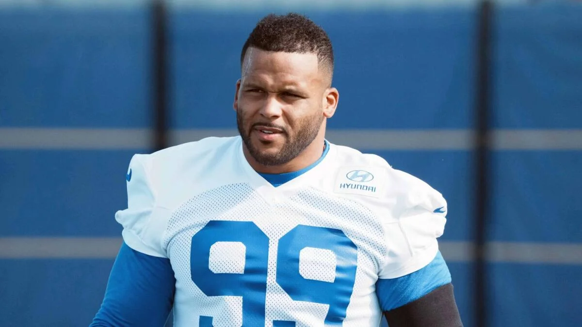 Football player in a white and blue Rams jersey poses during practice.