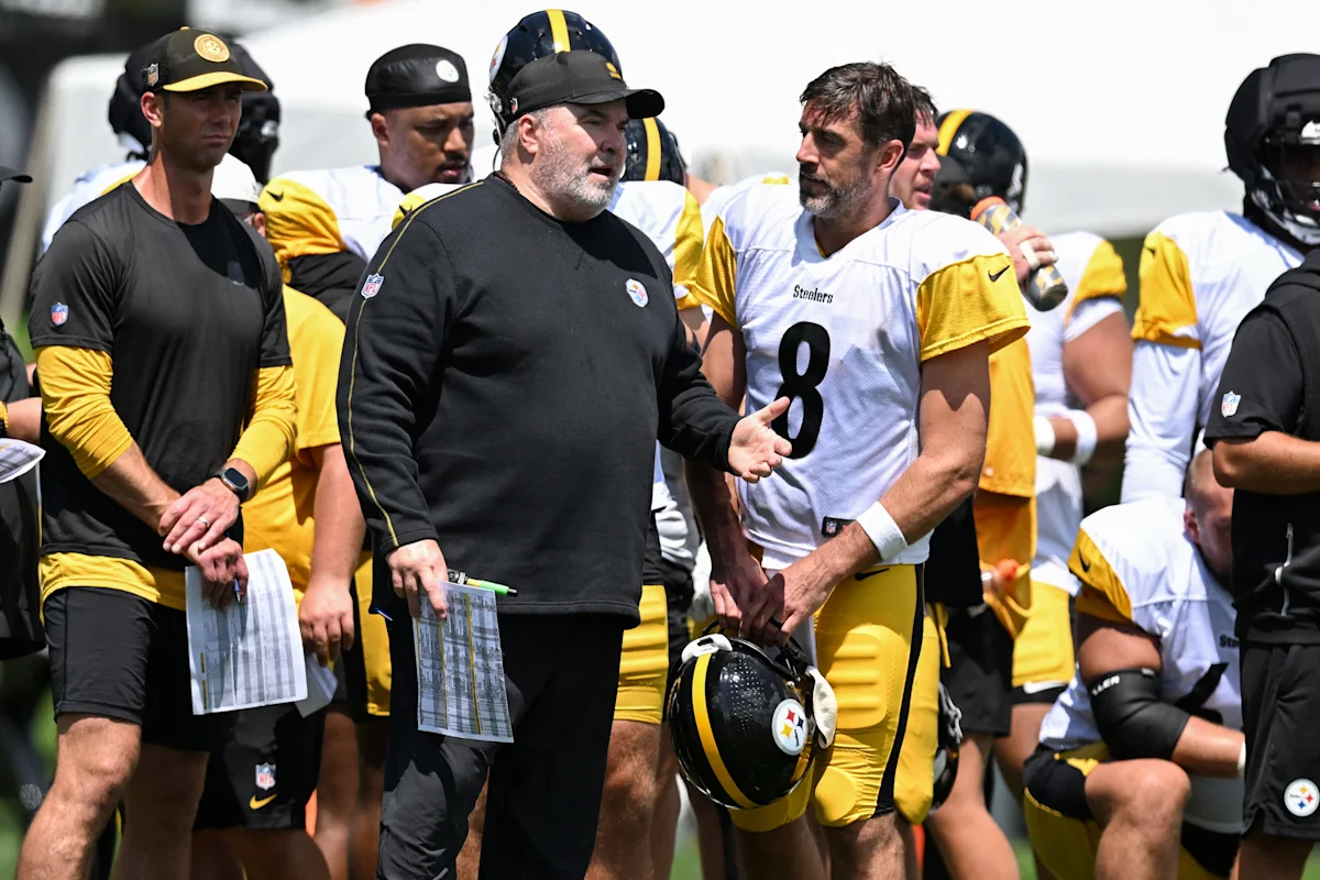 Football coach gestures beside quarterback Aaron Rodgers during a Pittsburgh Steelers practice session
