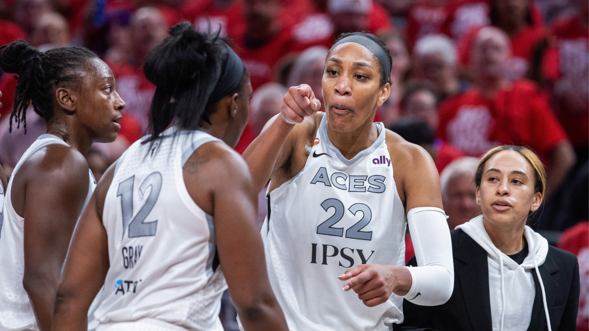 Aces players in white jerseys gather courtside as No. 22 gestures toward a teammate during a game.