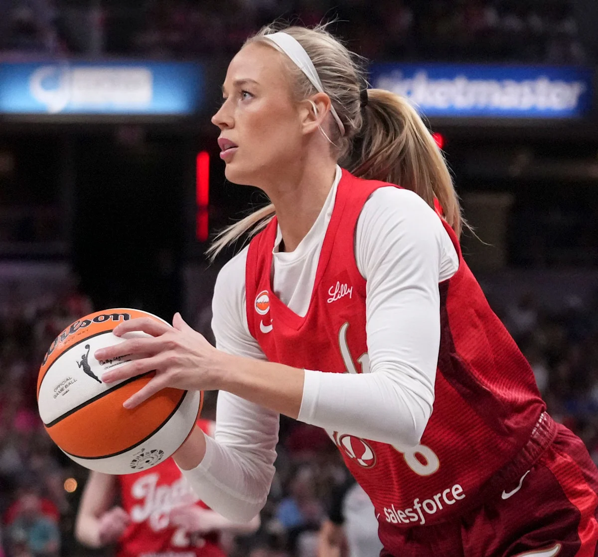 Basketball player in red jersey holds a basketball during an indoor game.