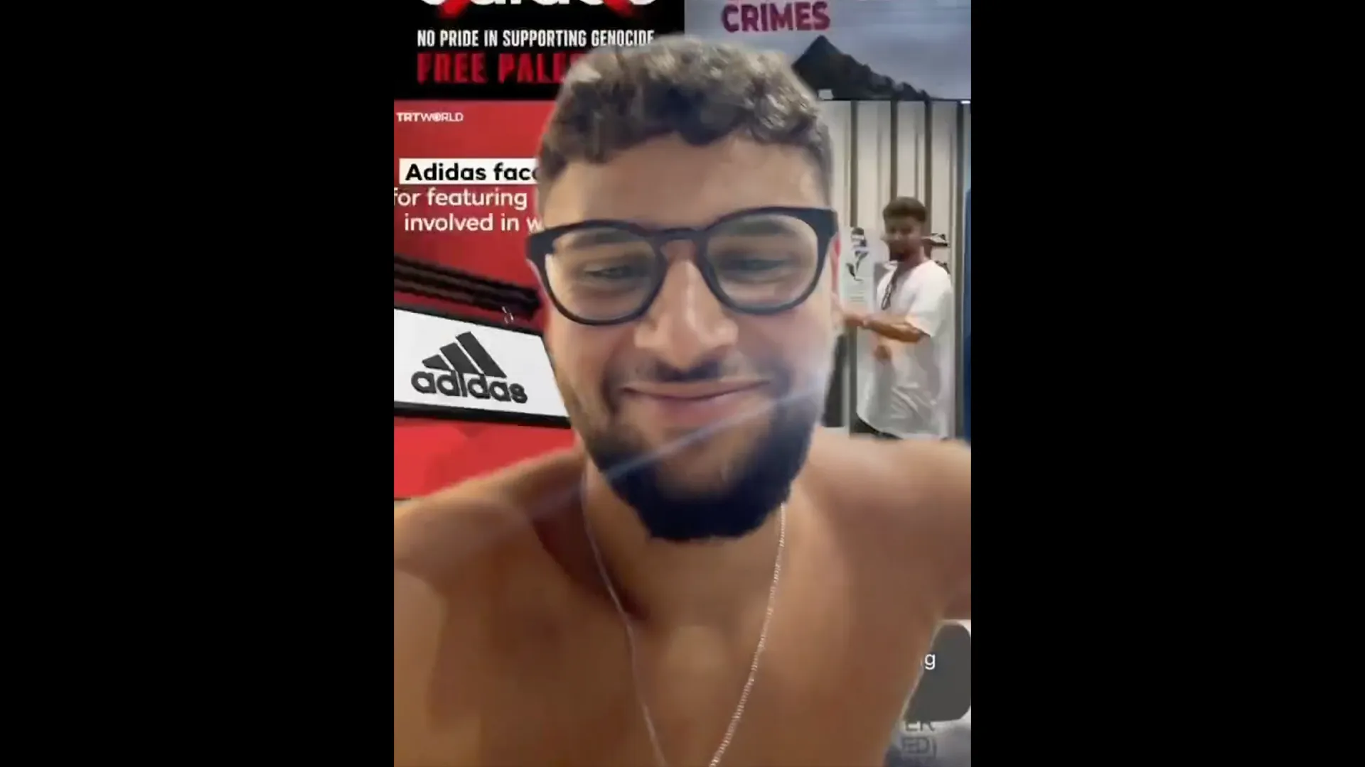 Smiling shirtless man wearing glasses and earbuds poses for a selfie indoors.