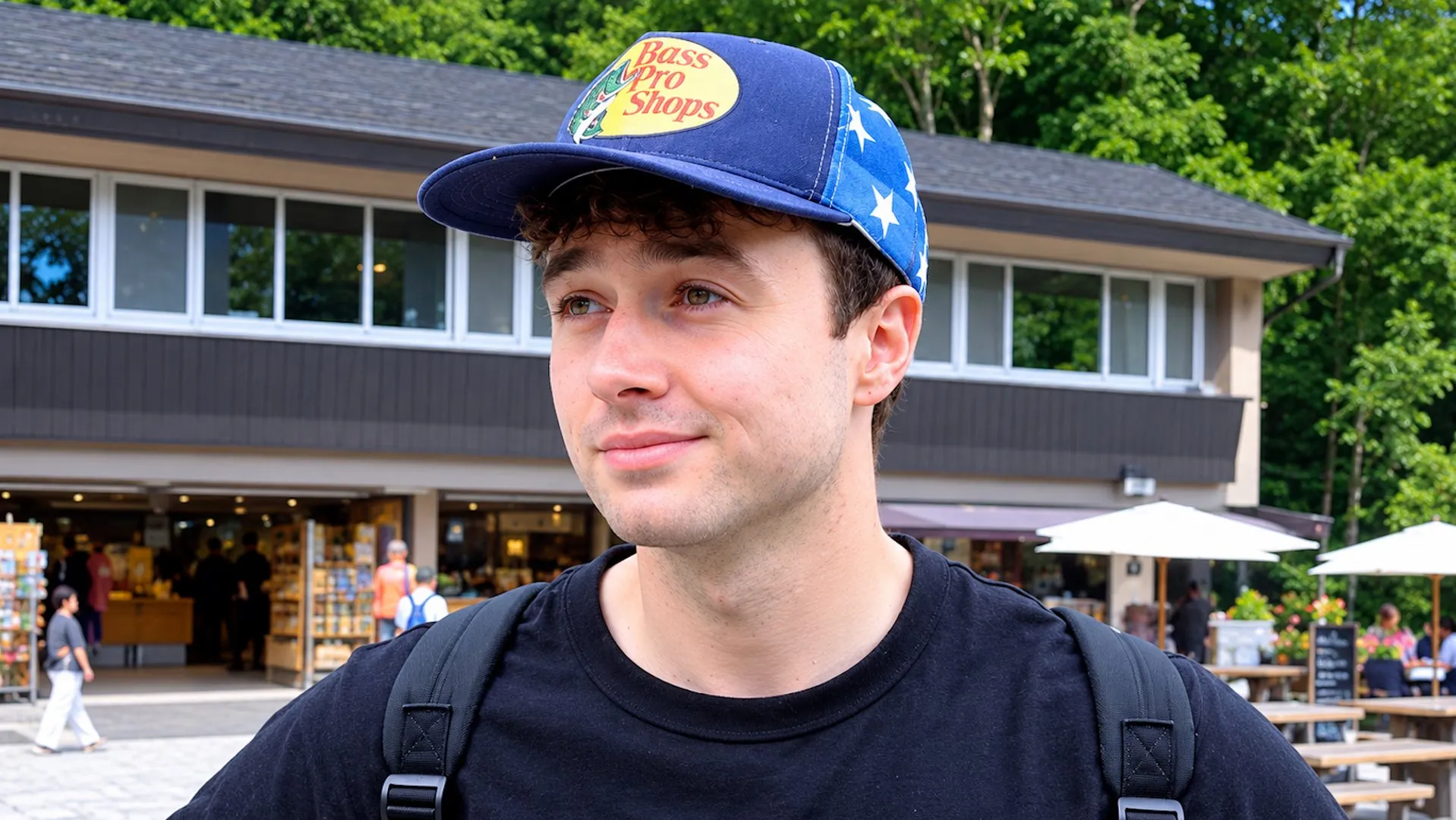 Young man wearing a Bass Pro Shops cap and backpack outside a building