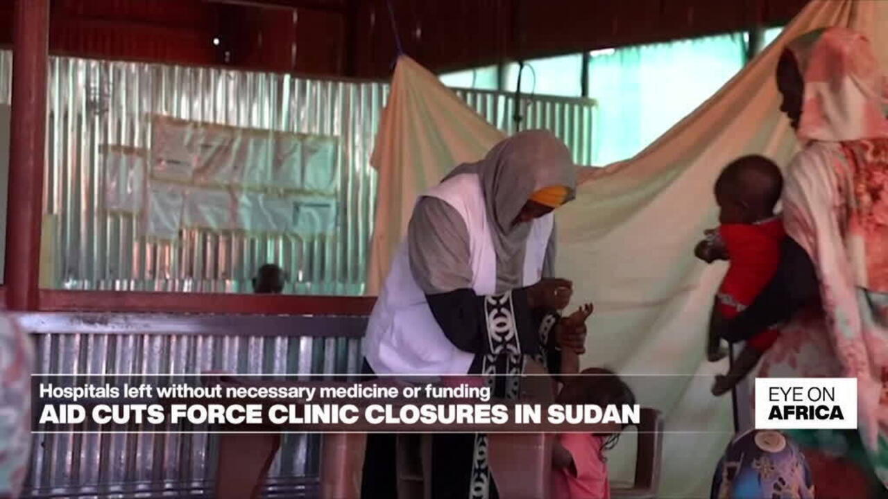 Healthcare workers and children inside a makeshift clinic with corrugated metal walls and fabric partitions.