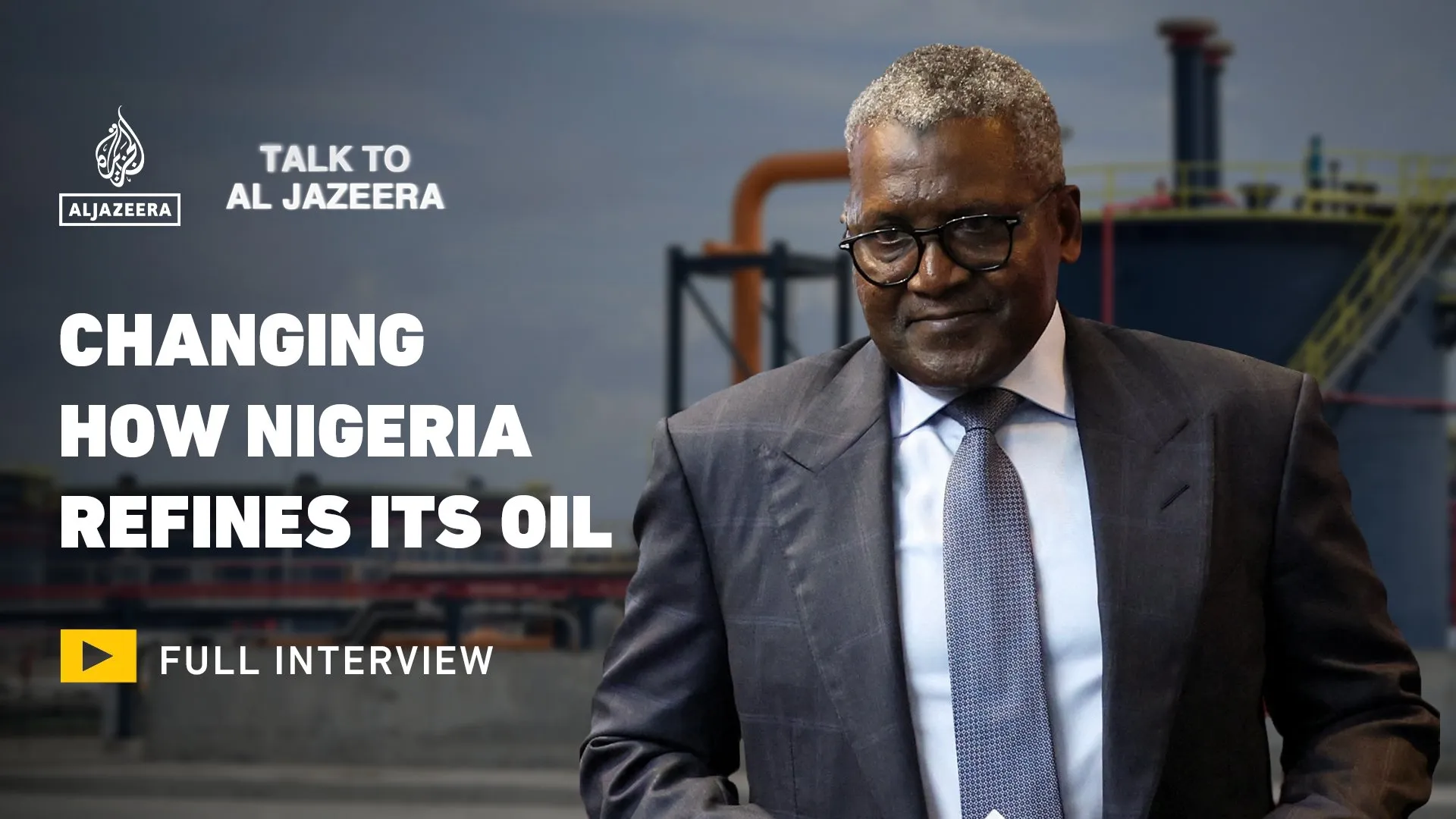 Suited man standing before an industrial oil refinery with Al Jazeera interview text overlay