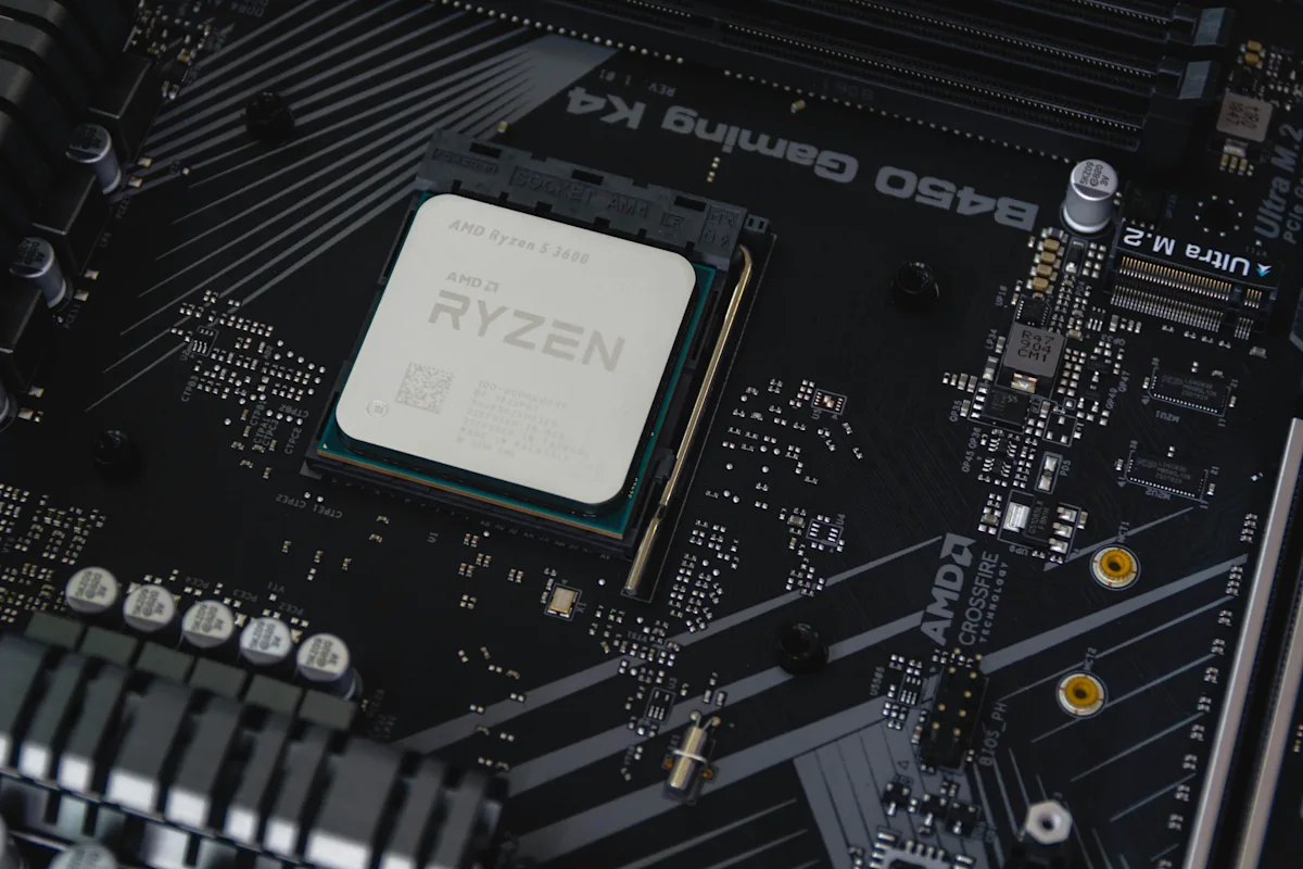 Close-up of an AMD Ryzen processor installed on a dark computer motherboard with circuit components.
