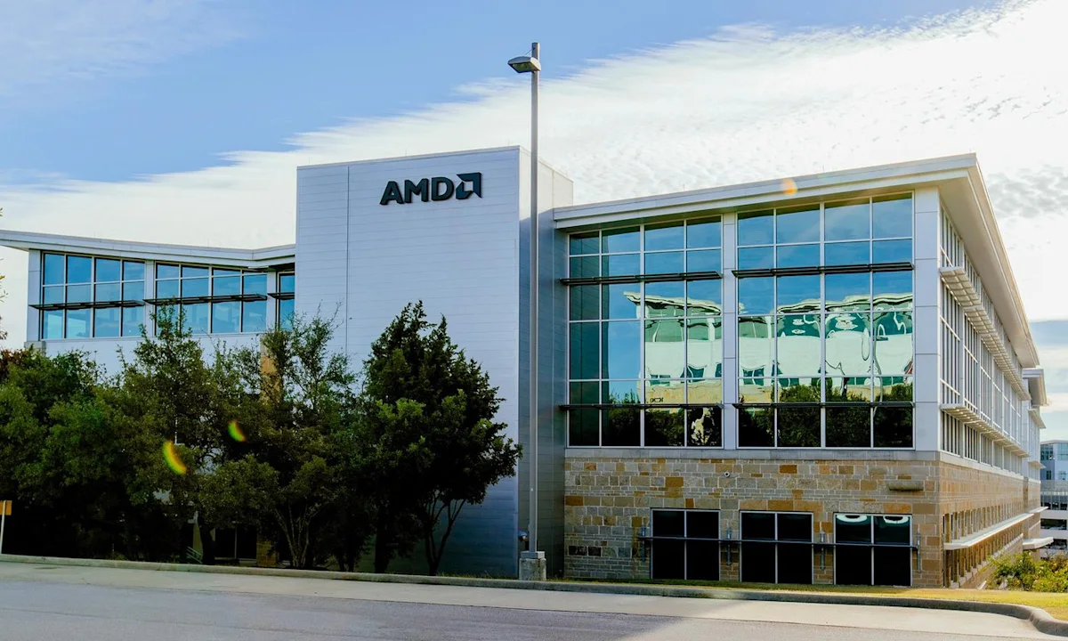 AMD office building with glass facade, trees, blue sky, and AMD logo above the entrance.