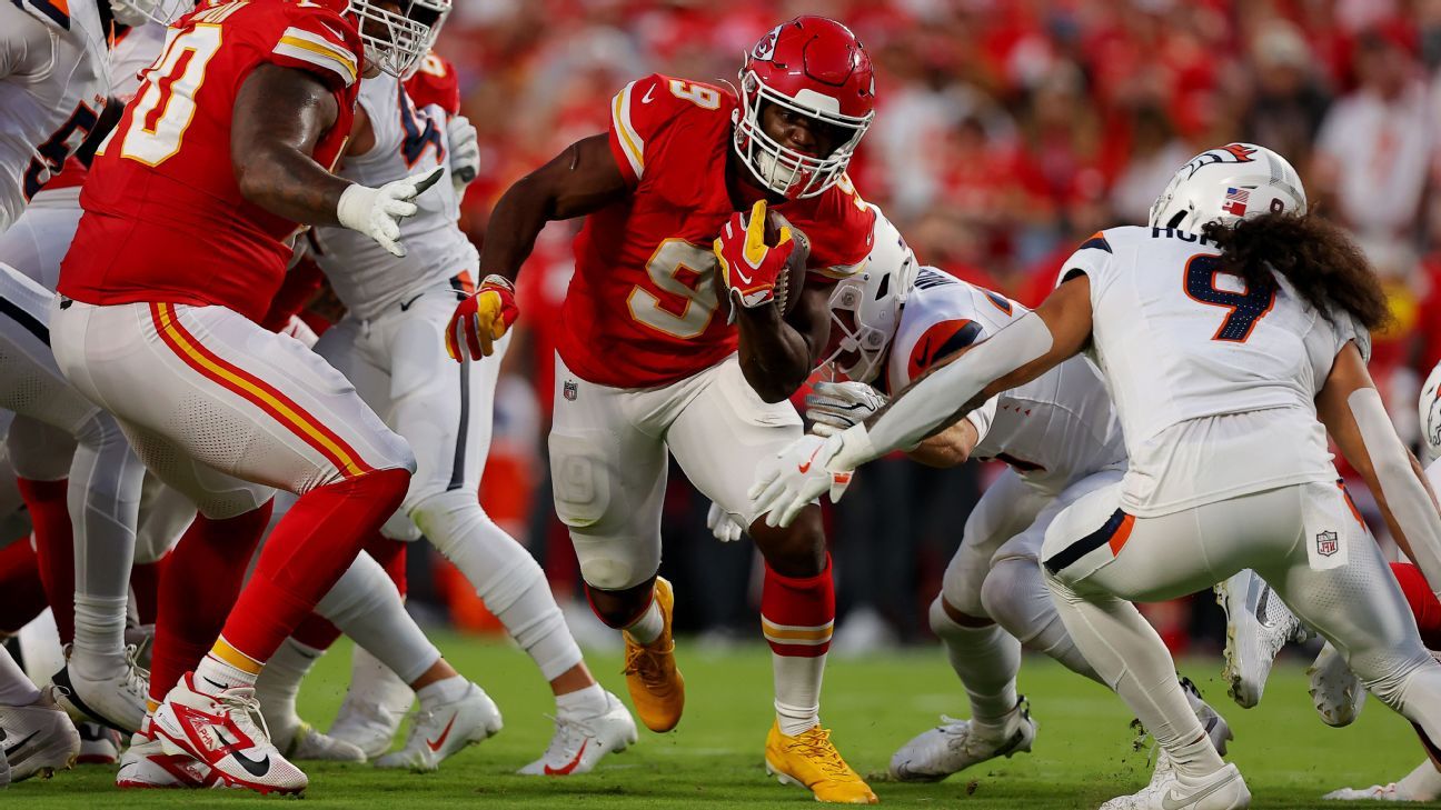 Kansas City runner carries the ball as Denver defenders converge during a football game.