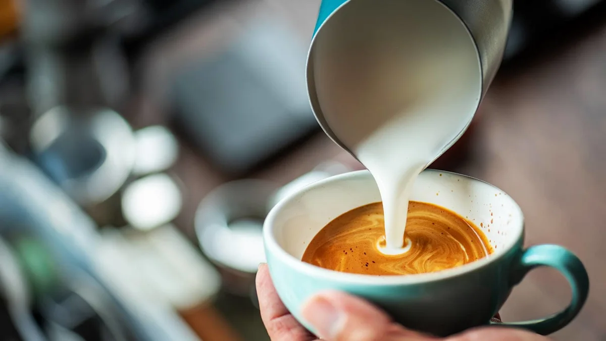 Milk is poured into a turquoise cup of espresso held by hand.