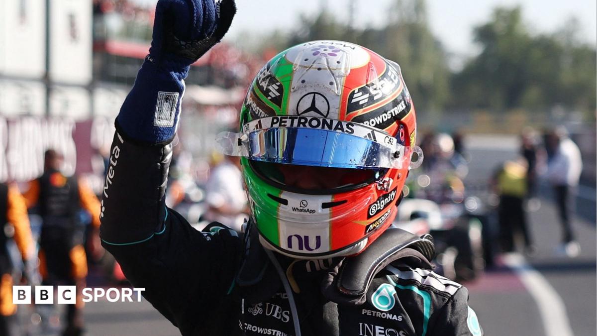 Helmeted racing driver raises a gloved fist during a Formula One event