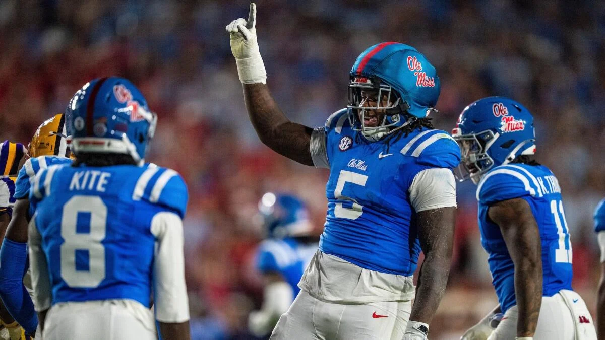 Ole Miss football players celebrate during a game, with No. 5 raising one finger.
