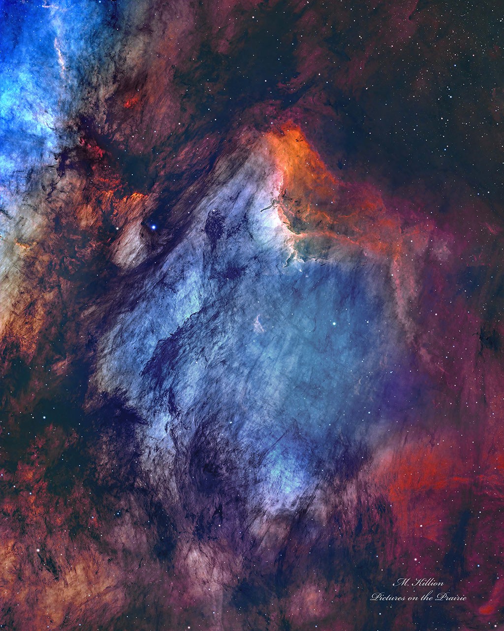 Colorful nebula of blue, red, orange, and purple gas clouds scattered with bright stars.