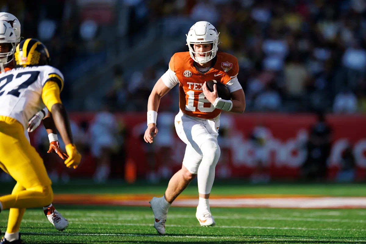 Texas quarterback in orange runs with the football as a yellow-clad defender approaches.