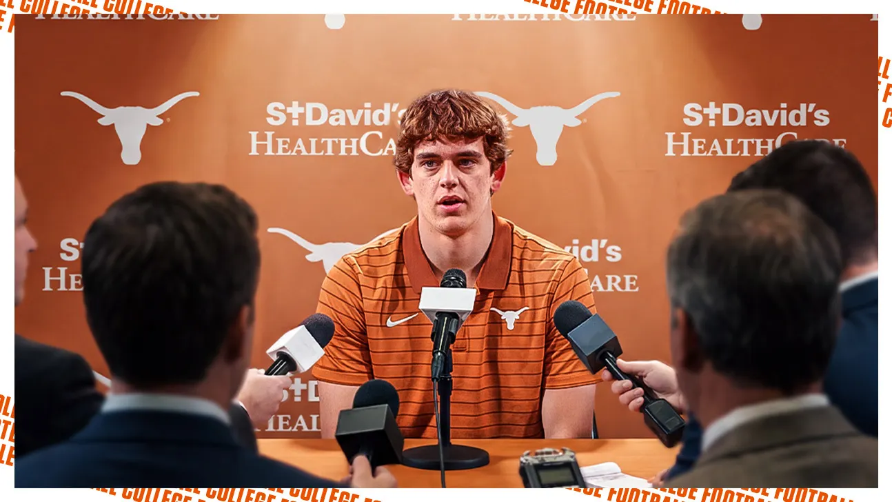Young athlete answers questions at a press conference while reporters hold microphones around him.